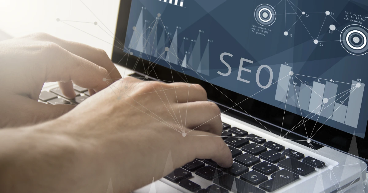 Hands typing on a laptop with an SEO analytics dashboard overlay showing bar charts and data visualisations