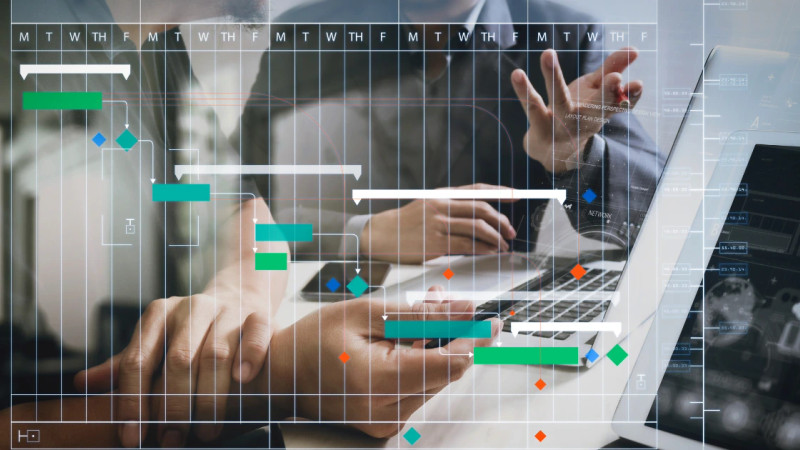 Digital Gantt chart overlay with coloured task bars over two people working at a laptop
