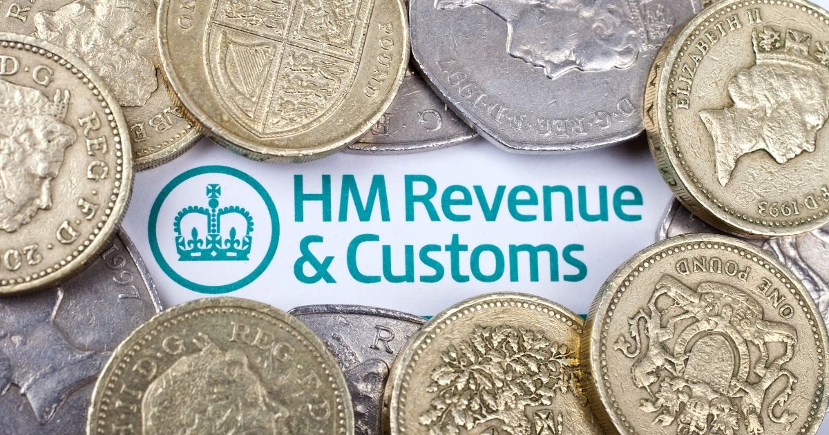UK pound coins scattered over a printed HM Revenue & Customs document showing the HMRC logo