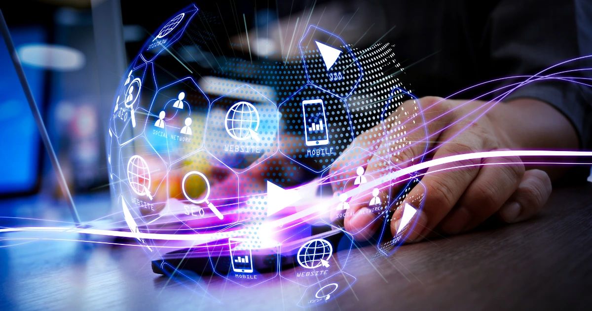 Hands on a desk with a glowing holographic sphere of digital marketing icons including SEO, website, mobile and social