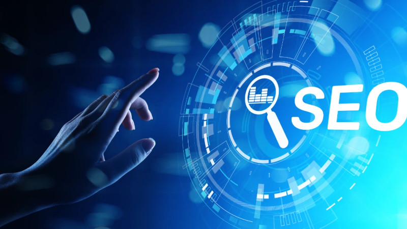 Hand pointing at a glowing blue digital interface displaying the word SEO and a magnifying glass icon