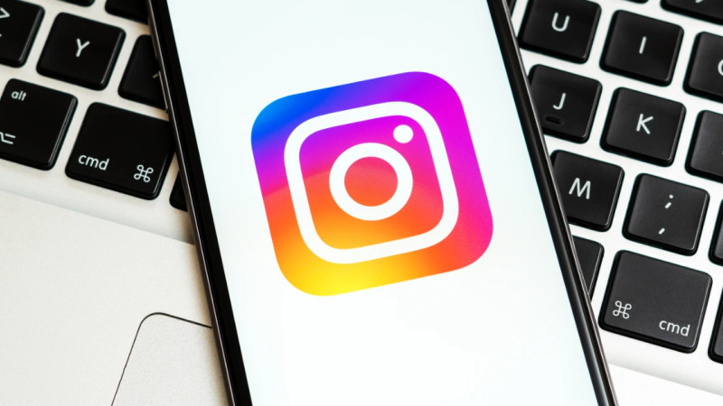 Smartphone displaying the Instagram app icon resting on a MacBook keyboard
