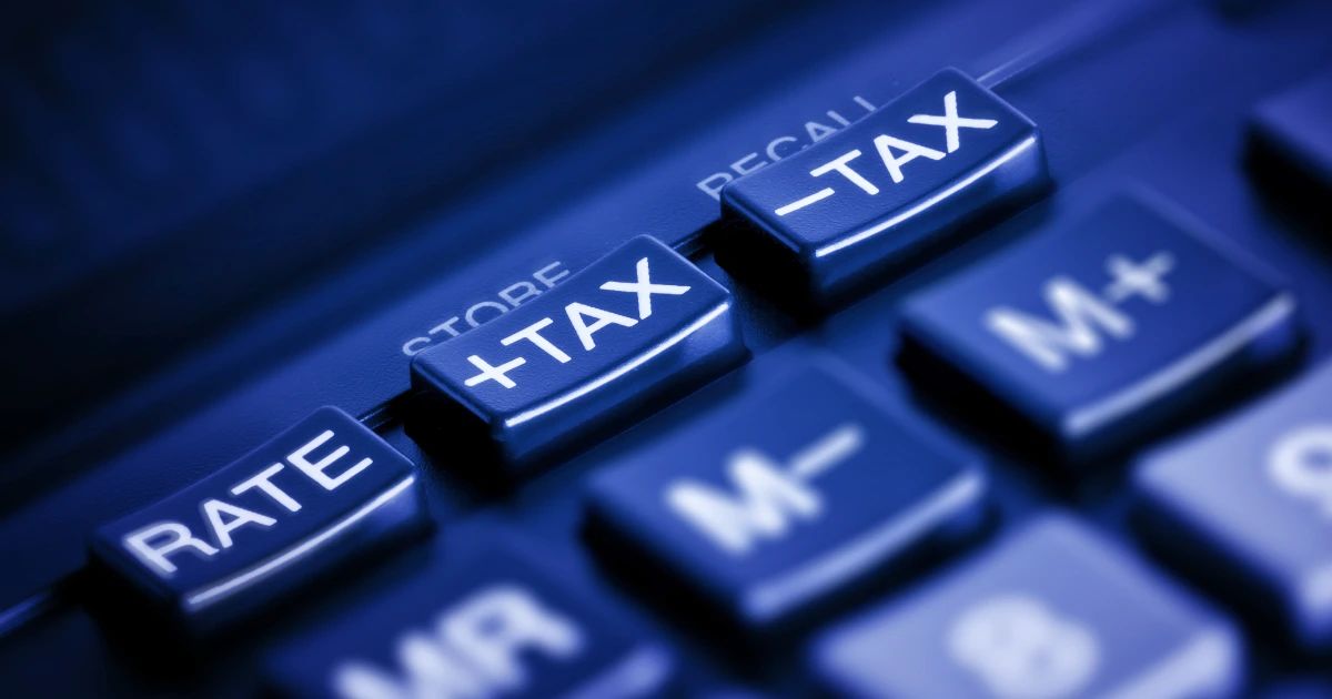 Close-up of a calculator keypad with +TAX and -TAX buttons highlighted in blue tones
