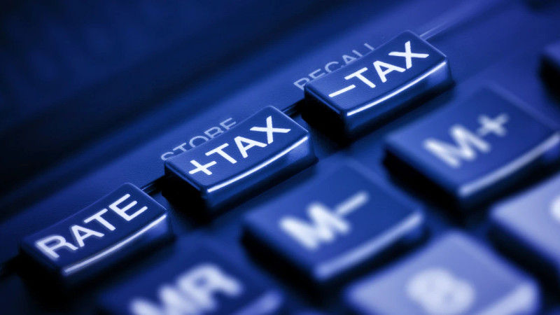 Close-up of a calculator keypad with +TAX and -TAX buttons highlighted in blue tones