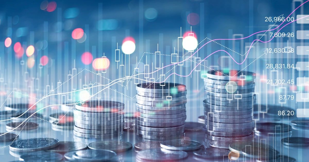 Stacked silver coins with digital candlestick chart and rising trend lines overlaid on blue bokeh background